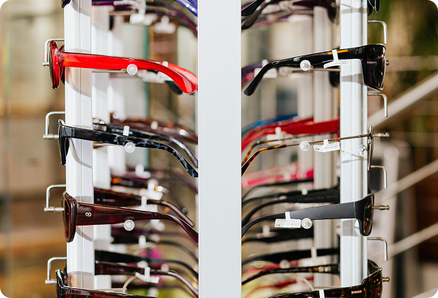 Display rack featuring multiple rows of eyeglass frames in assorted colors and styles at an optical shop.