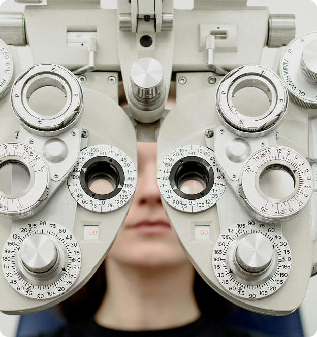A person undergoing a vision test using a phoropter at an optometrist's office.